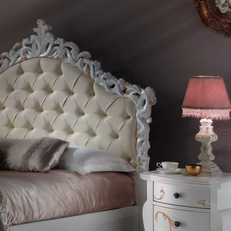 Dettaglio testata imbottita del letto con decori intagliati