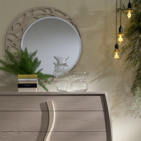 Specchiera tonda traforata in legno di frassino vicino a vasi decorativi