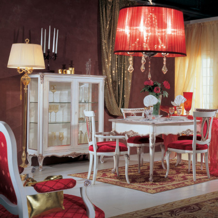 Tavolo intagliato allungabile ambientato con sedie rosse