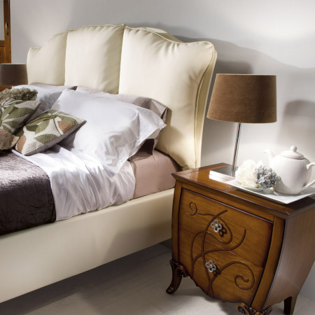 Specchiera con trafori in legno di noce vicino al letto